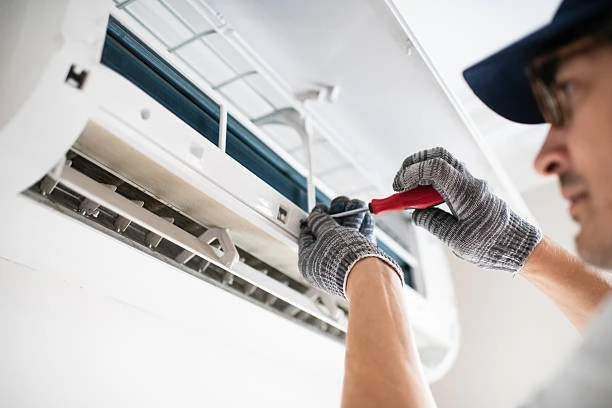 Gloved technician servicing a wall-mounted indoor air conditioning unit
