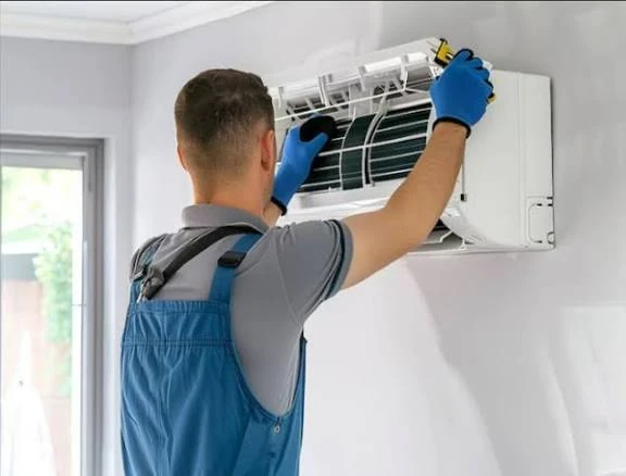 Technician opening a wall-mounted air conditioner for maintenance