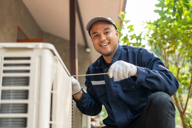Technician with service tools beside an outdoor air conditioning unit